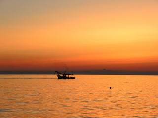Fototapeta na wymiar Fishing boats pull their nets at the sunrise. Adriatic cost. Emilia Romagna. Italy.