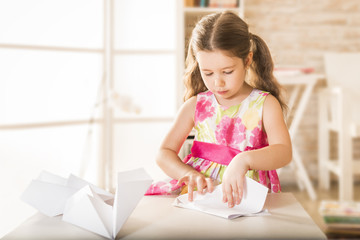 Adorable little girl playing with origami paper airplane. Little child doing paper airlpane. Children eduction concept. Kinder craft