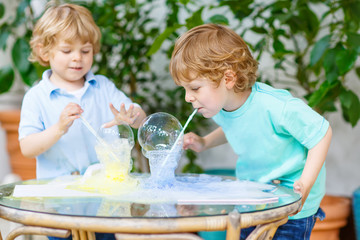 two twin boys making experiment with colorful bubbles