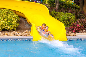 excited children in water park riding on slide with float
