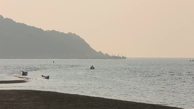 Misty tropical seascape with boats and fishermen silhouettes