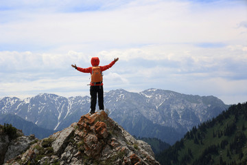 cheering woman hiker open arms on mountain peak