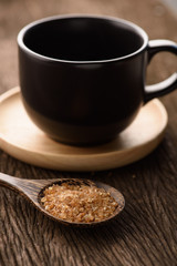 Raw Organic Cane Sugar in a wooden spoon with coffee cup