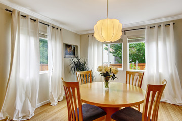 Cozy dining area with table set and curtains in creme tones.