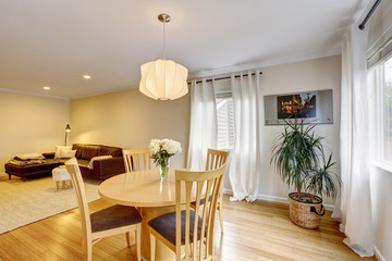 Cozy dining area with table set and curtains in creme tones.