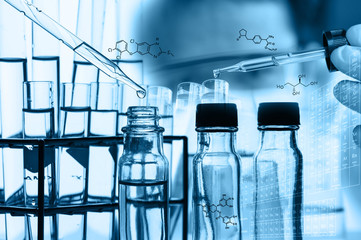 A researcher is testing, dropping reagent to test tube at laboratory with chemical equations and...