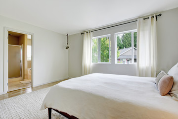 Bedroom interior in light tones with wooden bed and hardwood floor.