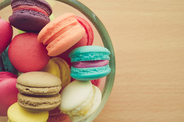 Fototapeta na wymiar Colorful france macarons in glass cup on wooden background.