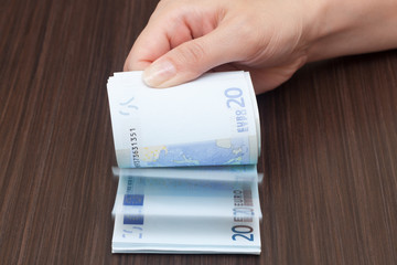 A woman is flipping cash money, euro currency, dark background