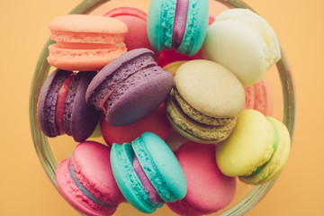Fototapeta na wymiar Colorful france macarons in glass cup on yellow background.