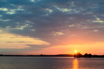 Fototapeta na wymiar Orange sunset over a european lake, blue clouds sky, colored dramatic scene