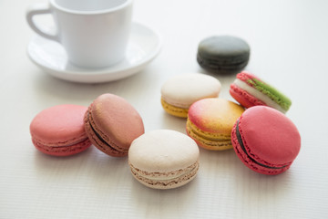 Colorful france macarons and cup on white wooden  background.