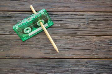 tape cassette, book and pencil on wooden background