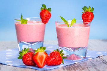 Glasses of strawberry smoothie on wooden table