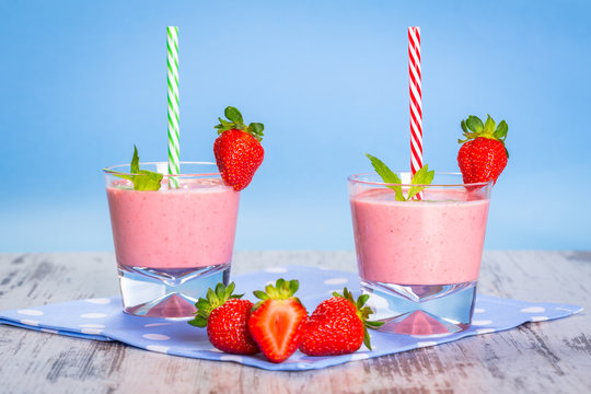 Glasses of strawberry smoothie on wooden table