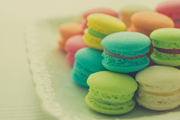 Fototapeta na wymiar Colorful france macarons on white vintage dish - retro color tone