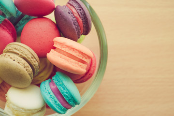 Fototapeta na wymiar Colorful france macarons in glass cup with wooden background. 