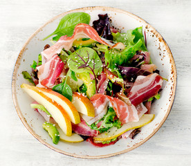 Fresh mixed salad with pancetta and pear.