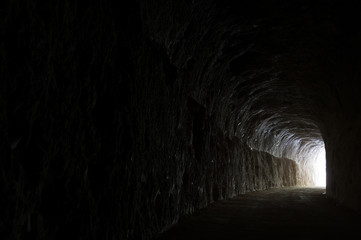 Dark road in a natural rocky tunnel and the light of the exit - 118675213