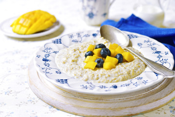 Oat porridge with mango and blueberry for a breakfast.