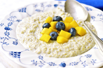 Oat porridge with mango and blueberry for a breakfast.