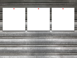Close-up of three square blank frames with red pins on gray old metal shutter background