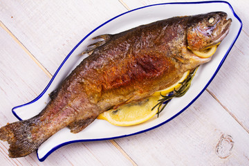 Whole grilled salmon fish on white wooden background. View from above, top studio shot