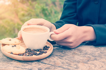 Woman in black holds coffee cup in her hands