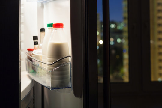 home fridge with milk bottles in night