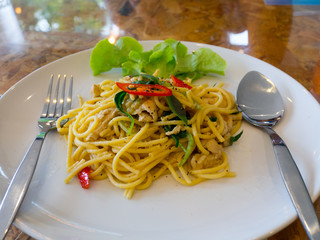 The Spaghetti , green curry with pork on a white plate. on the wooden table.
