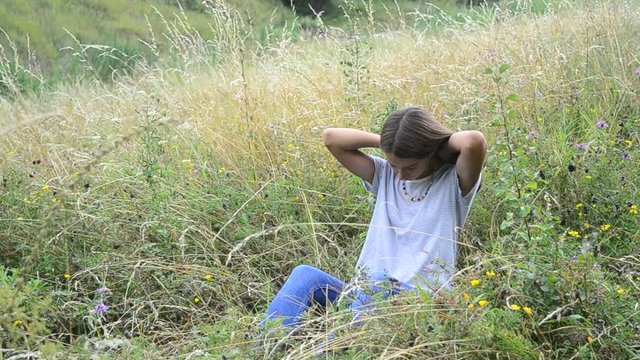 Girl sitting in grass wears beads on nature