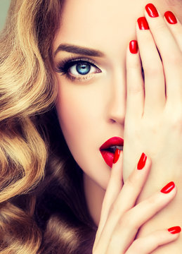 Beautiful  blonde model  girl  with long curly  hair . Hairstyle wavy curls . Red  lips and  nails manicure .   