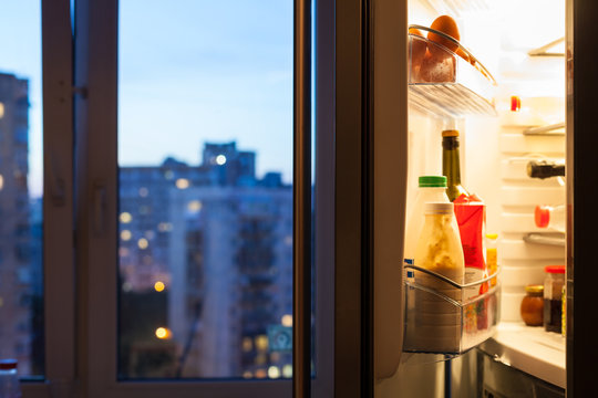 Open door of refrigerator with meal in evening