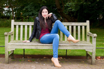 young woman sitting on a park bench posing