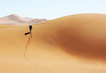 Mann laeuft durch die Wüste von Namibia