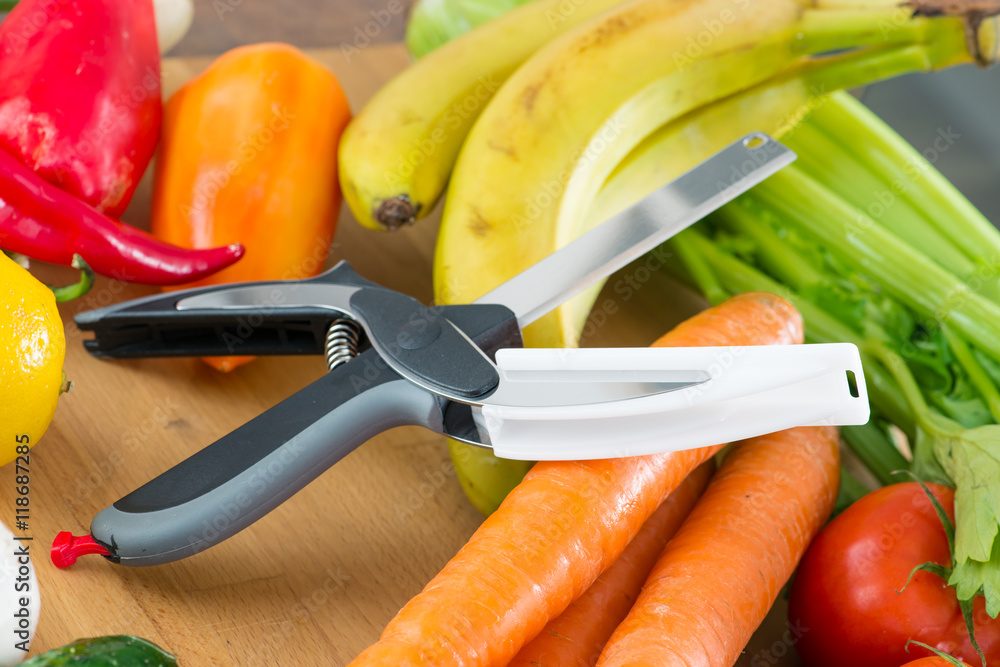 Poster knife-scissors in a pile of fresh vegetables