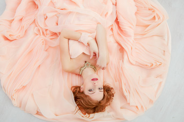Portrait of a beautiful girl in a beige peach dress in the Studio