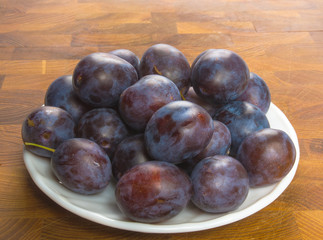 Fototapeta premium small plums on a white saucer
