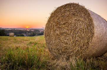 Strohballen auf einem Feld bei Sonnenuntergang.