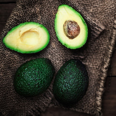 Halved avocado and whole  over rustic background.