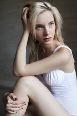 Obraz premium Portrait of beautiful blonde girl in white bodysuit on the black cube
