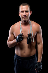 man with a skipping rope before a workout on a black background