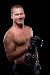 Fototapeta na wymiar Happy bodybuilder with dumbbell with a naked torso