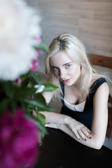 Portrait of beautiful girl blonde at table with flowers