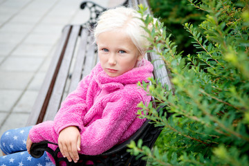 Portrait of a beautiful little girl sitting on a Park bench