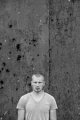 Portrait of the young man on background Rusty metal gate.
