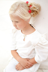 Portrait of beautiful little girl in a white dress near the columns