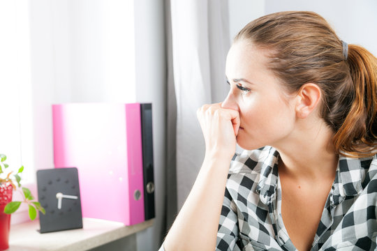 Desperate And Worried Woman In Home Office Looking At Window