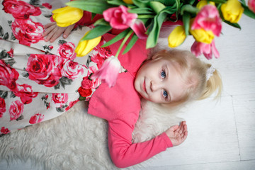 Portrait of a beautiful little girl with flowers on background of brick wall