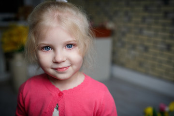 Portrait of a beautiful little girl with flowers on background of brick wall